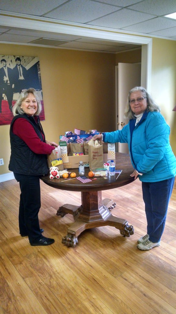 Two women show bags of donated items