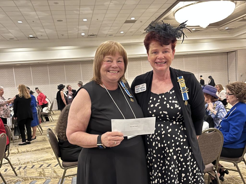 Two DAR members smile and hold a check for the Patawomeck Tribe of Virginia