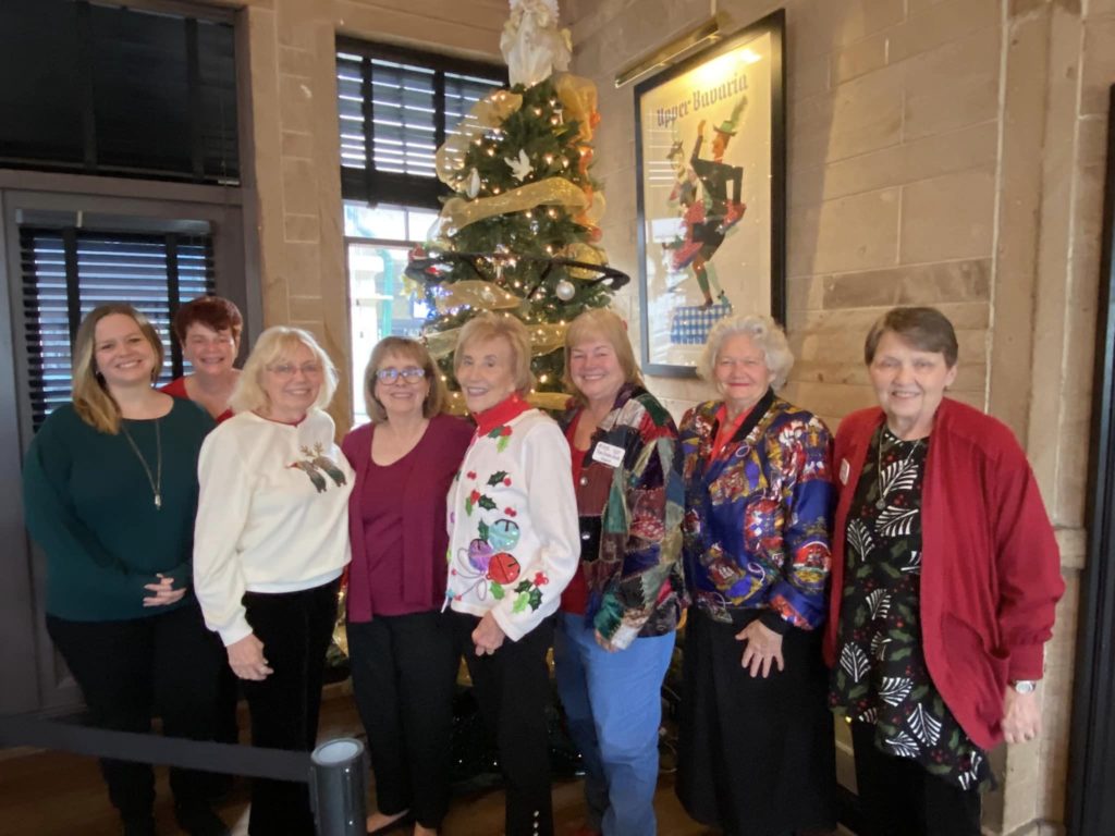 Members pose in front of a Christmas tree in holiday outfits